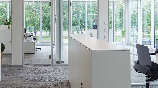Modernes Büro mit Glasfronten, weißen Schreibtischen und ergonomischem Arbeitsplatz