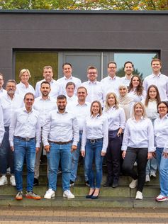 Die Mitarbeiter von Podufal-Wiehofsky stehen auf der Treppe vor dem Firmengebäude